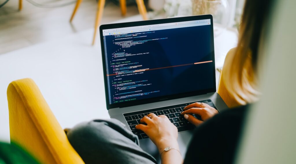 Young woman writes code on a laptop.