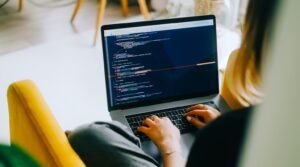 Young woman writes code on a laptop.