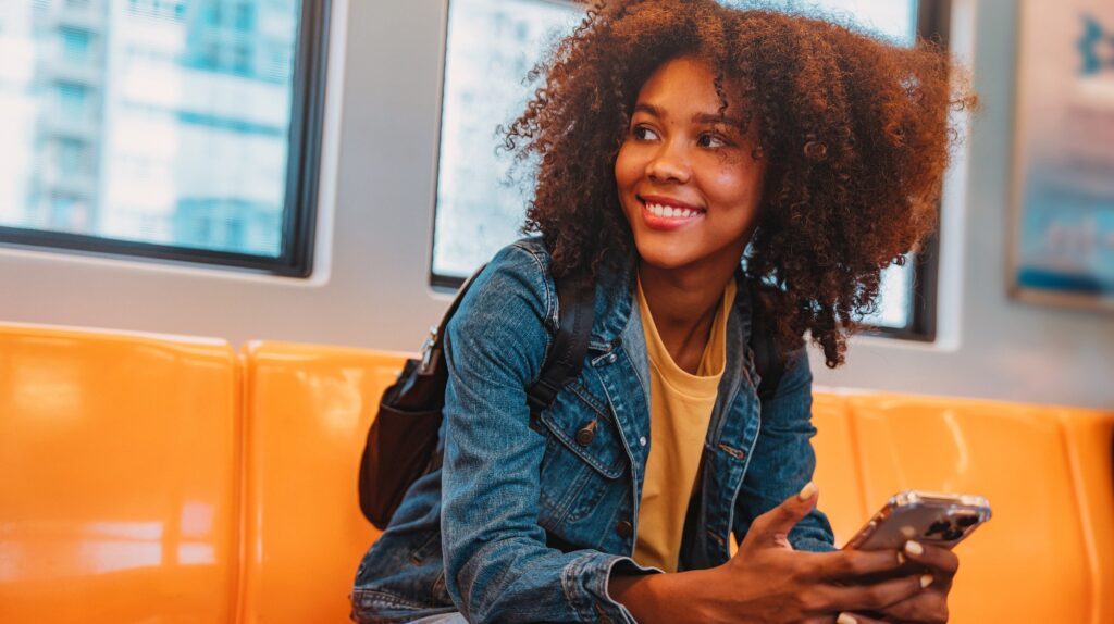 Young woman travelling by train accessing course information on her mobile device.