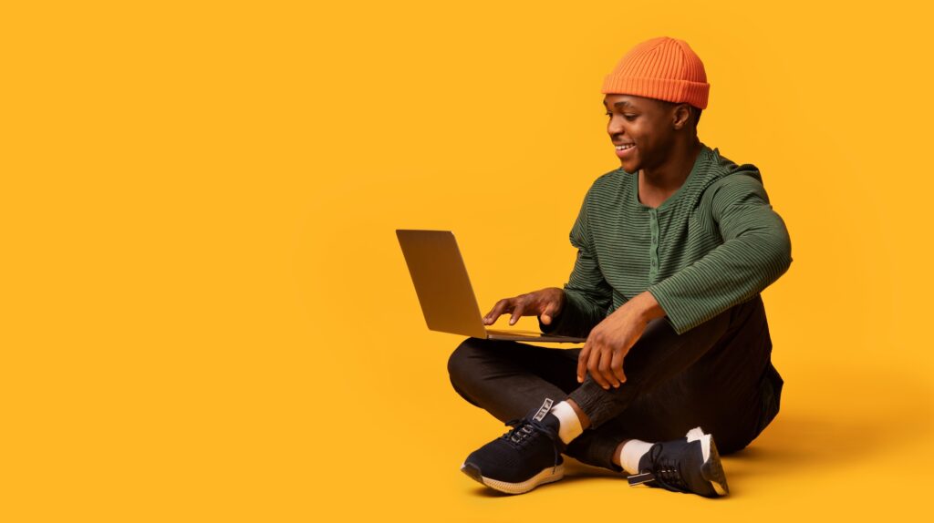 Young black male using his laptop for learning while sitting on the floor.