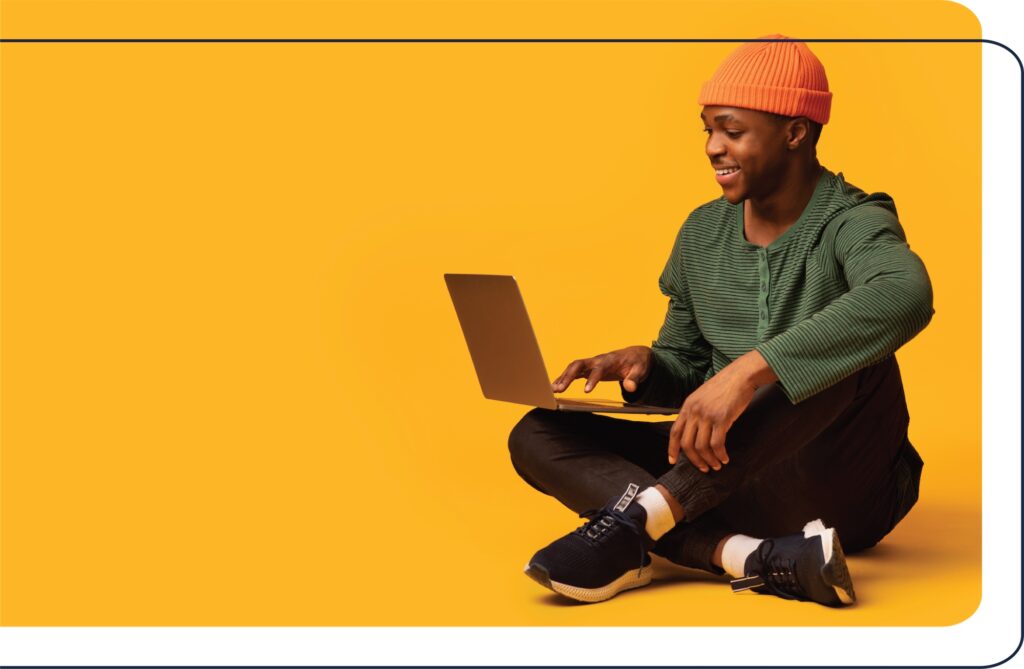 Young black student sitting on the floor crosslegged using a laptop